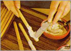 Untar los grisines separados en cinco grupos con las respectivas cremas, quedando, pues, un quinto grupo sólo con mantequilla.