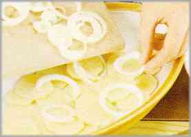 Cortar la cebolla en aros delgados, poniendo la mitad sobre las patatas, así como un picadillo de perejil y albahaca.