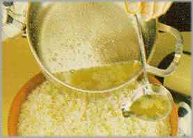 Escurrir el arroz, ponerlo en una fuente de servir junto con el resto de la mantequilla, condimentarlo con el jugo al ajo, pero sin el ajo, y espolvorear parmesano.