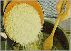 Incorporar el arroz, regándolo con caldo. Al final, añadir un poco de mantequilla y parmesano. Antes de llevar a la mesa, espolvorear el resto del queso.