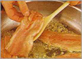 Calentar la mantequilla en una sartén grande, agregar la cebolla triturada y freír en ella los peces.