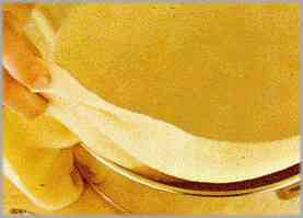 Untar con mantequilla un molde redondo y depositar la pasta más grande cubriendo los bordes.