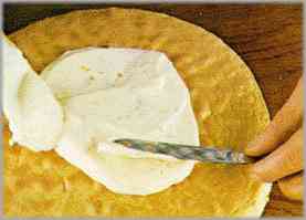 Cuando la tarta esté fría, cortarla transversalmente y untar la parte de abajo con parte de la crema. Montar la otra parte y untar el resto de la crema por toda la superficie. Adornar con gajos de naranja.