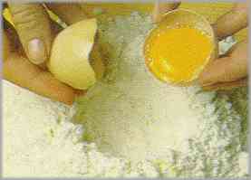 Colocar la harina en forma de cráter. En el mismo colocar un huevo entero, una pizca de sal y 100 gramos de mantequilla en trocitos.