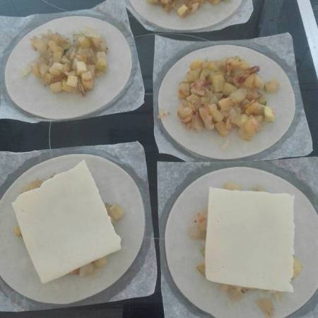 Cuando se ha enfriado o templado un poco, rellenamos las empanadillas con la mezcla y un trozo de loncha de queso.