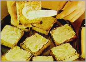 Cortar el pan en cuadraditos y tostarlos. Untarlos por un solo lado con mantequilla.