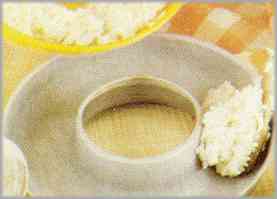 Poner el arroz, más bien líquido, en un molde redondo untado con mantequilla y dejarlo reposar diez minutos.