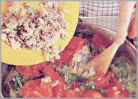 Faltando cinco minutos para retirar del fuego, poner en la cacerola los berberechos y los tomates. Condimentar con azafrán y pimentón y llevar a la mesa humeante.